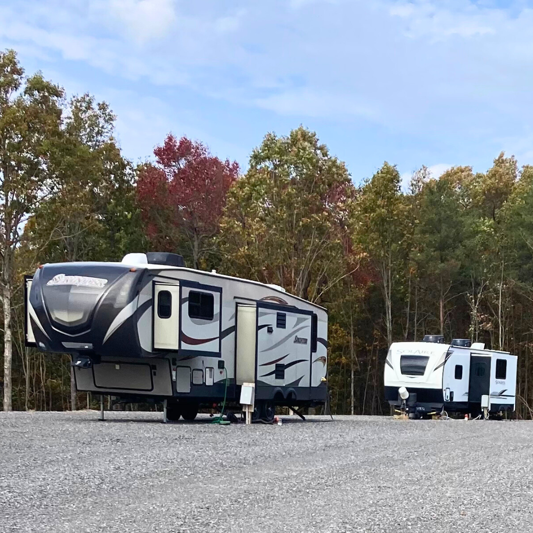 RV campsite with 2 rv campers and beautiful fall colors behind